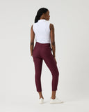 Woman wearing a white sleeveless top and maroon pants on a white background