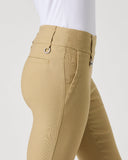 Close-up side view of a person wearing tan fitted pants with a white top, shown against a plain light gray studio background.