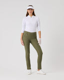 Woman in golf attire with a white shirt, green pants, and white shoes on a light gray background