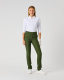 A woman modeling olive green tailored trousers with a white long-sleeve polo shirt and white gloves, standing against a light gray studio background.