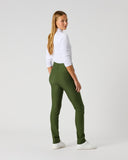 A woman modeling a pair of slim-fit olive green pants, paired with a white long-sleeve top and white sneakers, standing against a light gray studio background.