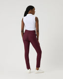 Person wearing burgundy pants and a white top on a light gray background