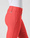 A close-up side view of a person wearing bright coral-red fitted pants with a white top, shown against a plain light gray studio background.