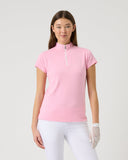Woman wearing a pink polo shirt and white pants on a light gray background