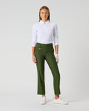 A woman modeling a white long-sleeve polo shirt and olive green cropped trousers, paired with white gloves and white sneakers, against a light gray studio background.