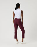 Person wearing a white top and maroon pants on a plain background