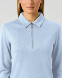 A woman wearing Daily Sports light blue Peoria long-sleeve quarter-zip polo shirt, shown from the nose down against a plain light gray studio background.