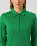 A woman wearing a bright green long-sleeve quarter-zip polo sweater, shown from the nose down against a light gray studio background.
