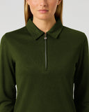 A woman wearing a dark olive green long-sleeve quarter-zip polo shirt, shown from the nose down against a light gray studio background.