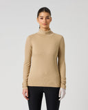 A woman modeling a beige ribbed mock neck long-sleeve top against a light gray studio background.