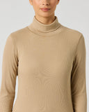A woman wearing a beige ribbed long-sleeve mock neck top, shown from the nose down against a light gray studio background.
