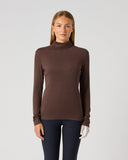 A woman modeling a ribbed brown mock neck long-sleeve top against a plain light gray studio background.