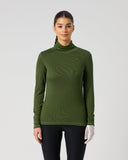 A woman modeling a ribbed long-sleeve turtleneck top in olive green, paired with black leggings, against a plain light gray studio background.