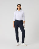 A woman modeling a white long-sleeve polo shirt and navy blue golf pants, standing against a light gray studio background.