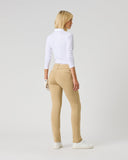 A woman with blonde hair is shown from behind wearing beige slim-fit jeans, a white long-sleeve top, and white sneakers, standing against a light gray studio background.
