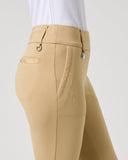 A close-up side view of a model wearing beige equestrian riding pants with a white shirt, shown against a light gray studio background.