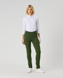 A woman modeling slim-fit olive green pants, paired with a white long-sleeve polo shirt and white sneakers, standing against a light gray studio background.