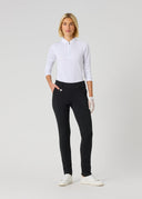 A woman modeling a white long-sleeve half-zip pullover and black fitted pants with white gloves and white sneakers, standing against a light gray studio background.