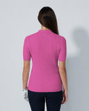 Woman wearing a pink ribbed sweater against a white background