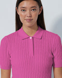 Woman wearing a pink ribbed polo shirt against a plain background