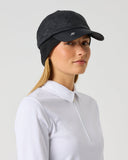 A woman wearing a black quilted baseball cap and a white long-sleeve polo shirt, shown in profile against a light gray studio background.