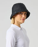 A woman wearing a black bucket hat and a white long-sleeve athletic top, shown in profile against a light gray studio background.