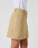A khaki A-line mini skirt with a front patch pocket, worn by a model in a white top against a light gray studio background.