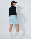 Person wearing a black jacket, light blue skirt, and white shoes on a plain background