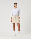 Person wearing a white shirt and beige skirt on a plain background