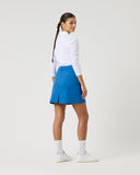 Person wearing a white long-sleeve shirt and blue skirt on a light gray background