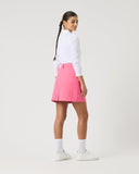 Person wearing a white shirt and pink skirt on a plain background