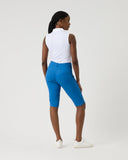 Person wearing a white sleeveless top and blue leggings on a plain background