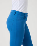 Blue riding pants worn with a white shirt on a light gray background