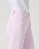 A close-up side view of a person wearing light pink tailored trousers with a white top, shown against a plain light gray studio background.