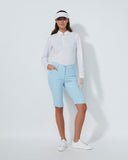 Woman wearing a white long-sleeve shirt, light blue shorts, and white sneakers on a white background