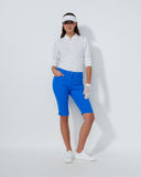 Woman in golf attire with blue pants and white shirt on a light gray background