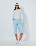 Woman wearing a white long-sleeve top, light blue pants, and a white visor on a white background