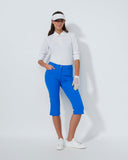 Woman in golf attire with blue pants, white shirt, and visor on a white background