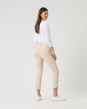 Woman wearing a white shirt and beige pants on a plain background