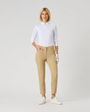 A woman modeling a white long-sleeve polo shirt and beige cropped trousers, standing against a light gray studio background.