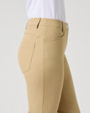A side view of a person wearing beige fitted pants and a white shirt against a light gray studio background.