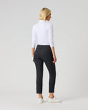A woman with blonde hair is shown from behind wearing black cropped trousers, a white long-sleeve top, and white sneakers against a light gray studio background.