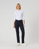 A woman modeling a white long-sleeve polo shirt and dark navy trousers, standing against a light gray studio background.