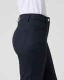 Close-up side view of a person wearing dark navy tailored trousers with a white top, shown against a light gray studio background.