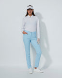 Woman wearing a white long-sleeve shirt, light blue jeans, and white sneakers on a gray background