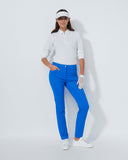 Woman in golf attire with blue pants, white shirt, and visor on a light gray background