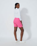 Person wearing pink shorts and a white shirt on a plain background