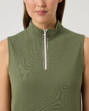 Woman wearing a green sleeveless top with a zipper on a light gray background