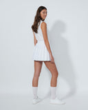Woman wearing a white dress and knee-high socks on a plain background