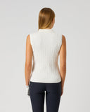 A woman viewed from behind wearing a sleeveless white ribbed knit mock-neck top and dark navy leggings, standing against a light gray studio background.